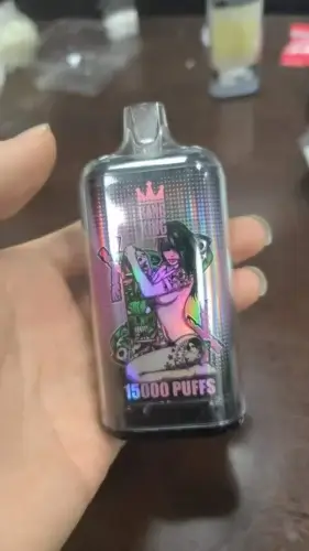 A hand holding a rectangular vape device labeled "15000 PUFFS" with a graphic of a woman hugging a large, green monster.